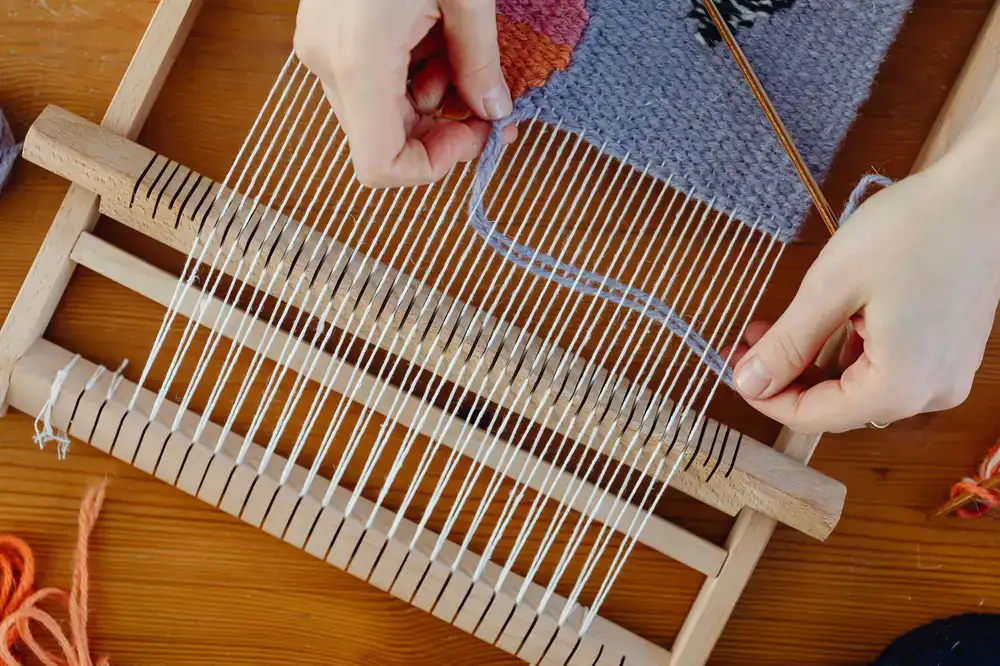 A craftsperson examining a woven wool panel in a bright studio